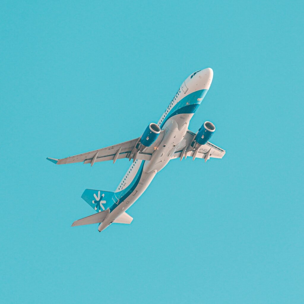 A low angle shot of an airplane flying through a clear blue sky in Karachi, Pakistan.