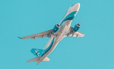 A low angle shot of an airplane flying through a clear blue sky in Karachi, Pakistan.